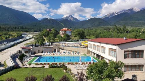 a hotel with a pool and mountains in the background at private apartment hotel Regnum Bansko in Bansko