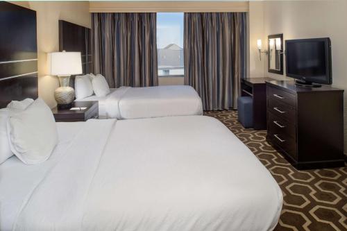a hotel room with two beds and a flat screen tv at Embassy Suites by Hilton St Louis Airport in Bridgeton