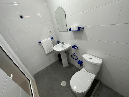 a white bathroom with a toilet and a sink at Decifer Sport Resort in Belas