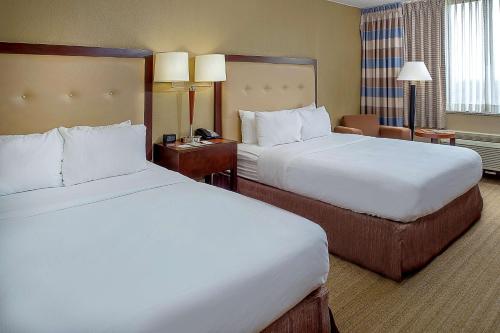 a hotel room with two beds and a desk at DoubleTree by Hilton St. Louis at Westport in Maryland Heights