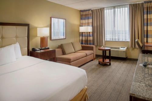 a hotel room with a bed and a couch at DoubleTree by Hilton St. Louis at Westport in Maryland Heights