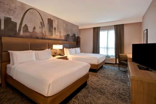 a hotel room with two beds and a flat screen tv at DoubleTree by Hilton St. Louis Airport, MO in Woodson Terrace