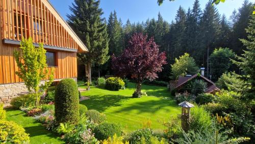 a garden in front of a house with trees at Pension Linda in Harrachov