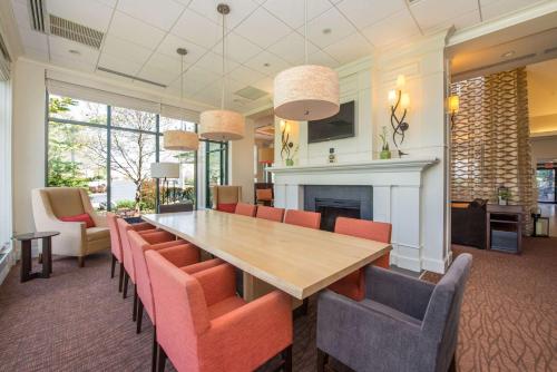 Hilton Garden Inn Fishkill في فيشكيل: غرفة طعام مع طاولة وكراسي ومدفأة