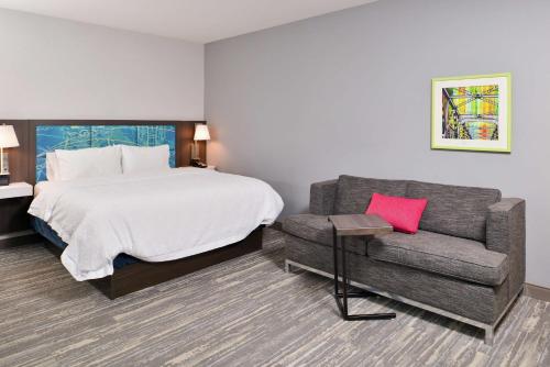 a hotel room with a bed and a couch at Hampton Inn & Suites Saint Paul Oakdale Woodbury in Woodbury