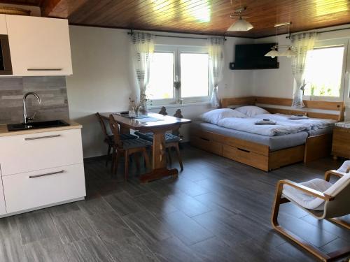 a bedroom with a bed and a table and a kitchen at Chata Trhovky 1 in Milešov