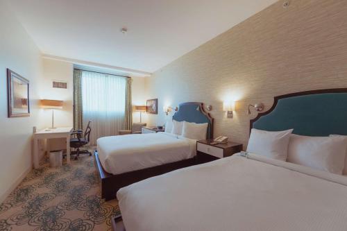 a hotel room with two beds and a desk at Hotel Skyler Syracuse, Tapestry Collection by Hilton in Syracuse