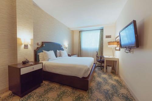 a hotel room with a bed and a flat screen tv at Hotel Skyler Syracuse, Tapestry Collection by Hilton in Syracuse