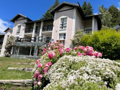 a house with pink flowers in front of it at Aldea Andina Hotel&Spa in San Carlos de Bariloche