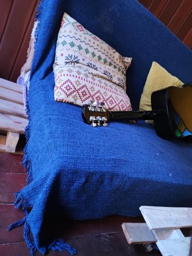 gitara siedząca na niebieskim kocu obok poduszki w obiekcie Ganesha Hostel w mieście Pipa