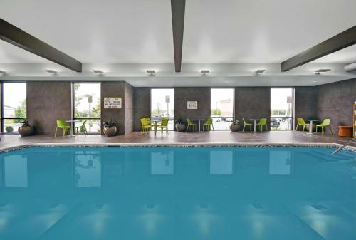 a pool in a hotel with green chairs and tables at Home2 Suites By Hilton Utica, Ny in Utica