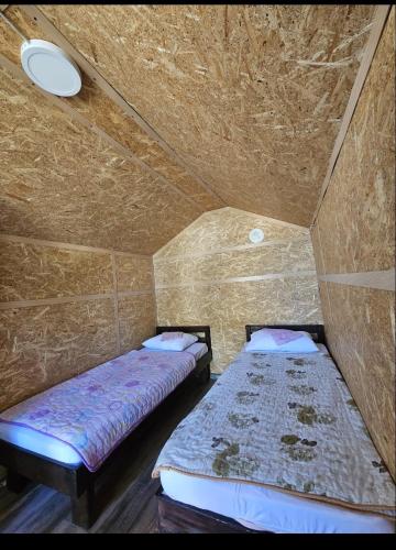 two beds in a small room with a ceiling at Camp Miroc water in Brza Palanka