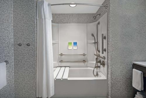 a bathroom with a tub and a shower with a shower curtain at Home2 Suites By Hilton Utica, Ny in Utica