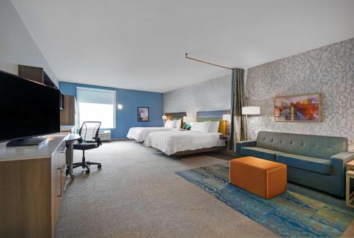 a hotel room with a bed and a couch and a tv at Home2 Suites By Hilton Utica, Ny in Utica