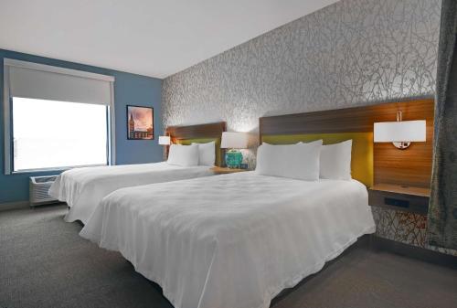 a hotel room with two beds and a window at Home2 Suites By Hilton Utica, Ny in Utica