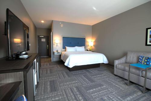 a hotel room with a bed and a couch at Hampton Inn West Plains in West Plains