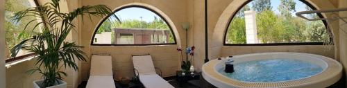 ein Badezimmer mit einer großen Badewanne und 2 Fenstern in der Unterkunft Trulli Aurasia in Ostuni