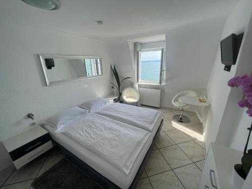 a white bedroom with a bed and a window at Hotel la Perla in Meersburg
