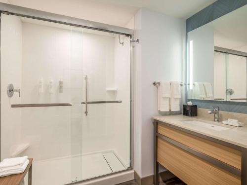 a bathroom with a glass shower and a sink at Hilton Garden Inn Toledo Downtown in Toledo