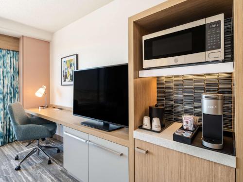 a hotel room with a desk with a television and a microwave at Hilton Garden Inn Toledo Downtown in Toledo