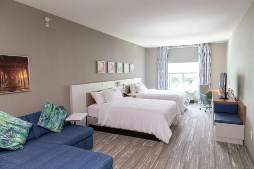 a hotel room with two beds and a couch at Hilton Garden Inn Tampa - Wesley Chapel in Wesley Chapel