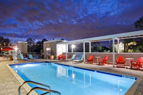 - une piscine de nuit avec des chaises et des tables dans l'établissement Home2 Suites By Hilton Tampa USF Near Busch Gardens, à Tampa