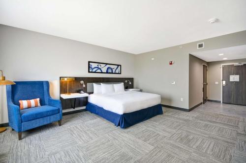 a hotel room with a bed and a blue chair at Hilton Garden Inn Tulsa-Broken Arrow, OK in Broken Arrow