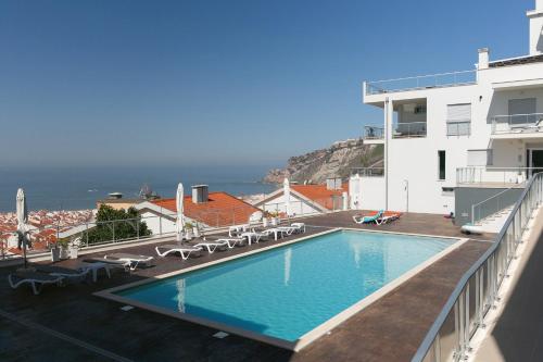 una piscina con sedie e l'oceano sullo sfondo di Oceanview Dreamer's Delight a Nazaré