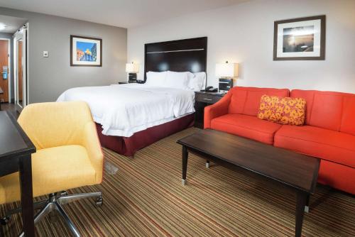 ブロークン・アローにあるHampton Inn Tulsa/Broken Arrowのベッド1台と赤い椅子2脚が備わるホテルルームです。