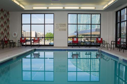 a swimming pool with tables and chairs and windows at Hampton Inn & Suites Tulsa Downtown, Ok in Tulsa