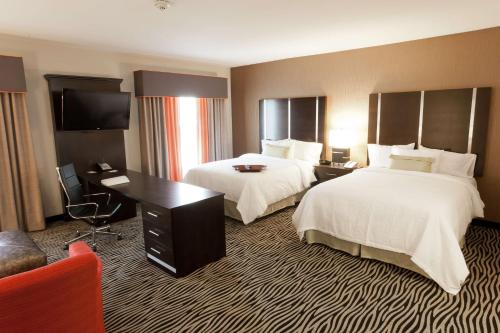 a hotel room with two beds and a desk at Hampton Inn and Suites Tulsa Central in Tulsa