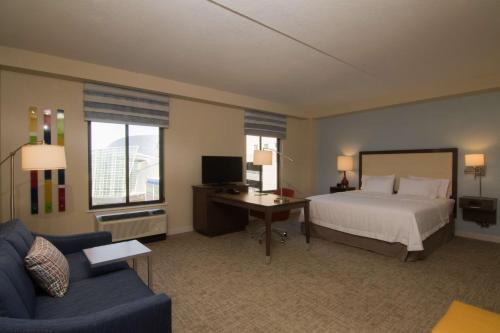 een slaapkamer met een bed, een bureau en een bank bij Hampton Inn & Suites Tulsa Downtown, Ok in Tulsa