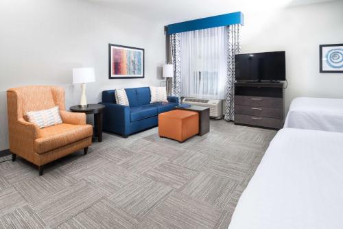 a hotel room with a bed and a couch and a tv at Homewood Suites By Hilton Tulsa Catoosa in Catoosa
