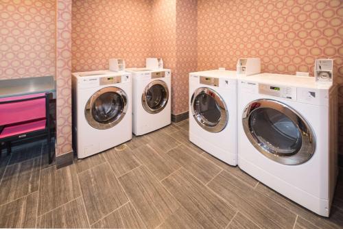 three washing machines and a tv in a laundry room at Homewood Suites By Hilton Tulsa Catoosa in Catoosa