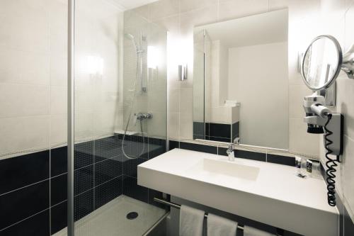 ヴィルールバンヌにあるHôtel Mercure Lyon Centre Charpennes Parc de la Tête d'Orの洗面台とシャワー付きの白いバスルーム