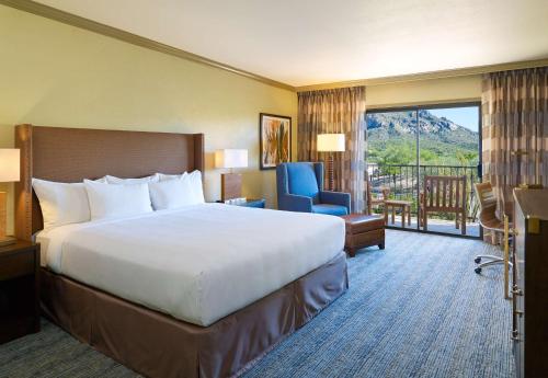 a hotel room with a large bed and a balcony at El Conquistador Tucson, A Hilton Resort in Tucson