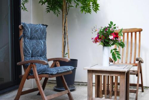 a wooden rocking chair next to a table with a vase of flowers at Maison Coté Jardin Amiens - Longueau in Longueau