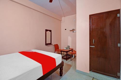 a bedroom with a bed and a table with a chair at Hotel O New Mayuri Lodge in Bāgepalli