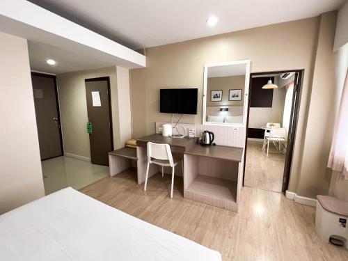 a hotel room with a desk and a bedroom at Srivichai Hotel in Nakhon Ratchasima