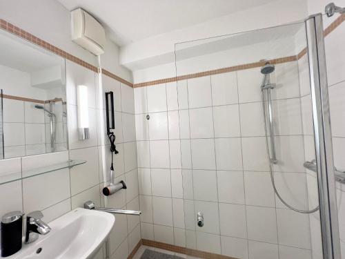 La salle de bains est pourvue d'une douche et d'un lavabo. dans l'établissement Zentrale Apartments im Herzen vom Bremerhaven, à Bremerhaven