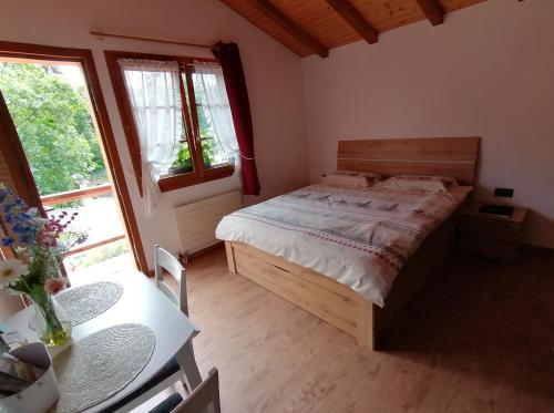 a bedroom with a bed and a table and windows at Les Comblés des Combes in Ollon