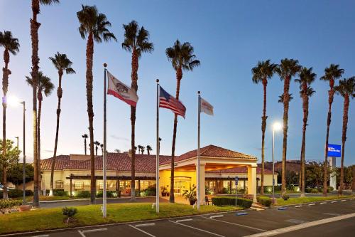a hotel with palm trees in front of a building at Hilton Garden Inn Valencia Six Flags in Valencia