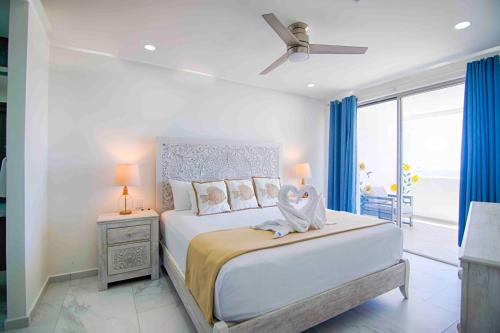 a white bedroom with a large bed with a ceiling fan at Casa Blanca Golf Villas in Puerto Peñasco