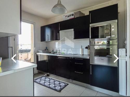 une cuisine avec des armoires noires et un four à plaques de cuisson dans l'établissement T3 Annemasse 4eme étage Proche Genève, à Annemasse