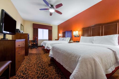 a hotel room with two beds and a flat screen tv at Hampton Inn & Suites Boulder North in Boulder