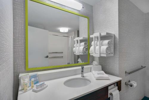a bathroom with a sink and a large mirror at Hampton Inn Utica in Utica