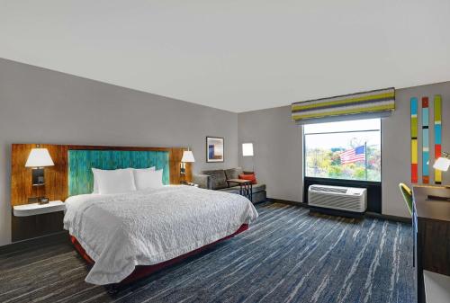 Hampton Inn Utica في أوتيكا: غرفه فندقيه بسرير ونافذه