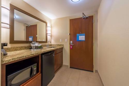 ein Badezimmer mit einem Waschbecken, einem Spiegel und einer Tür in der Unterkunft Hampton Inn & Suites Boulder North in Boulder