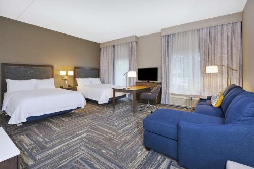 Habitación de hotel con 2 camas y sofá azul en Hampton Inn & Suites Wells-Ogunquit en Wells