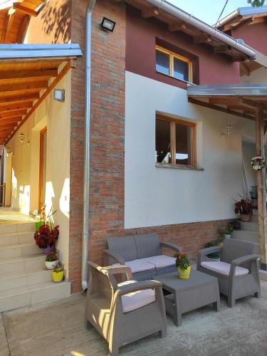 a patio with chairs and tables in front of a building at IKONIJA guest house in Pečenjevce